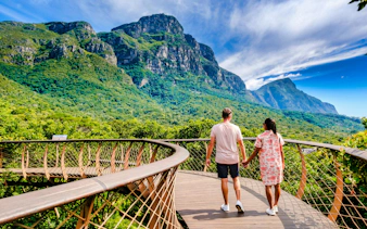 Couple walking on canopy bridge at Kirstenbosch Gardens with mountain view.