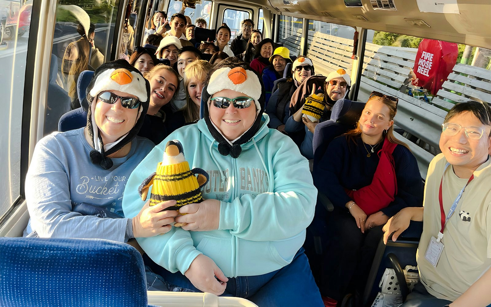 Tourists wearing penguin hats on a coach to Phillip Island.