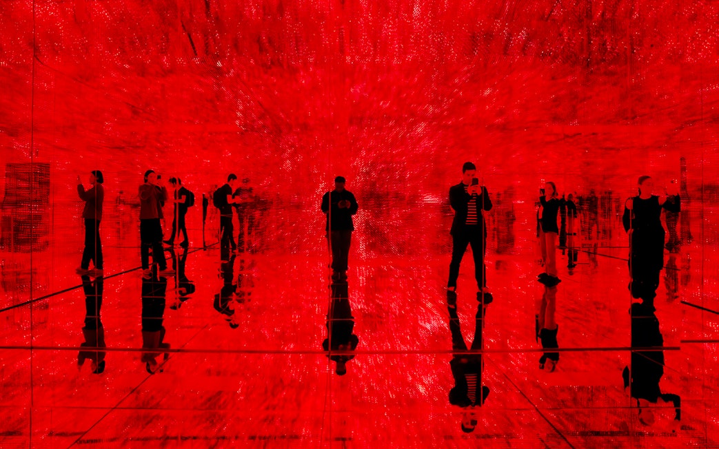 Visitors exploring immersive red light exhibit at Mercer Labs, Museum of Art & Technology.