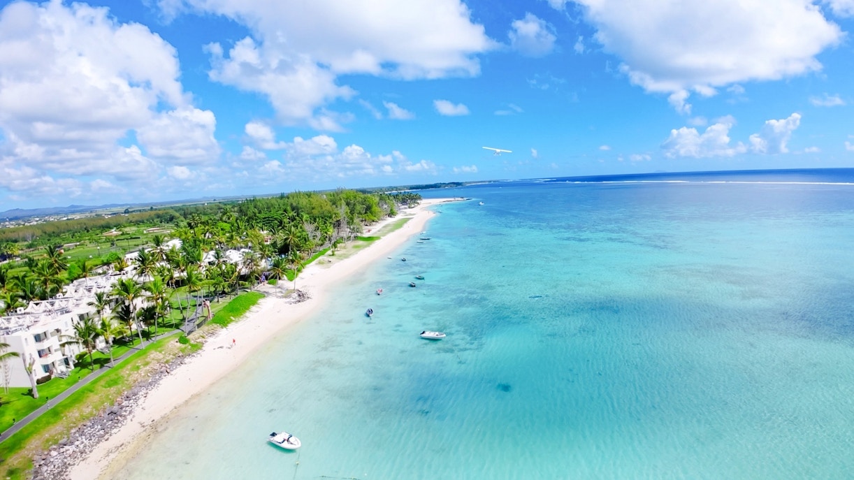 Aerial view of Mauritius coastline with seaplane over turquoise waters on Short Amber Route Scenic Tour.