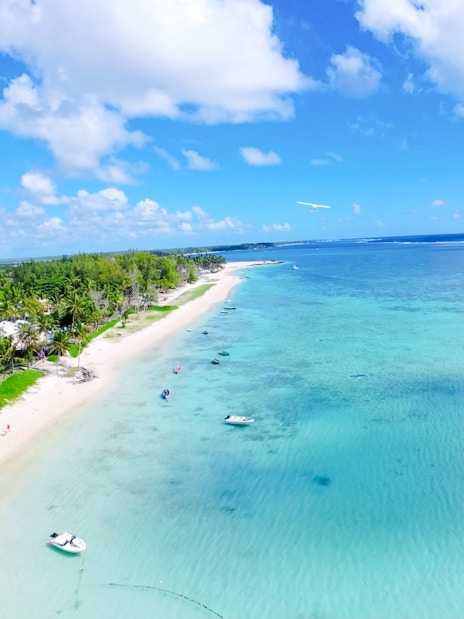 Aerial view of Mauritius coastline with seaplane over turquoise waters on Short Amber Route Scenic Tour.
