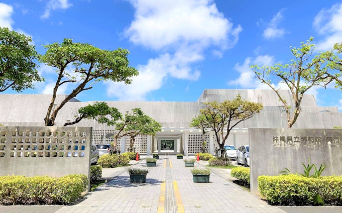 Okinawa Prefectural Museum and Art Museum entrance with trees and pathway.