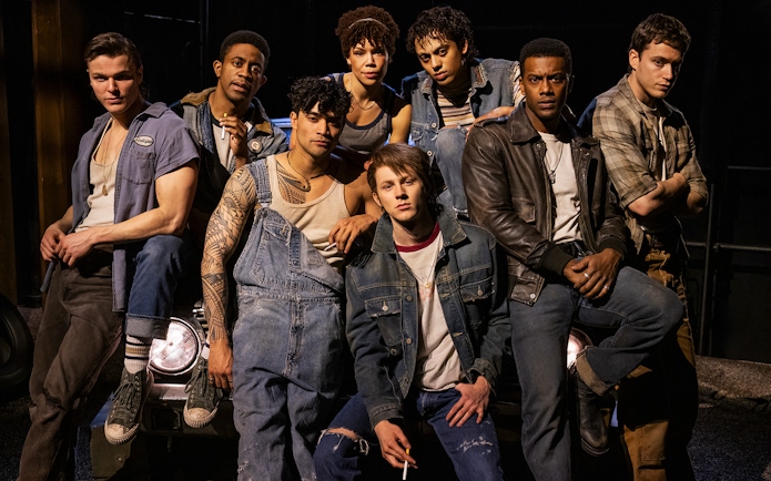 Group of young men in denim and leather jackets from "The Outsiders" stage production.