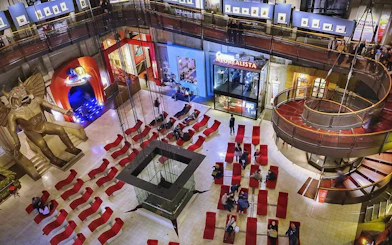 Visitors in the atrium of the National Museum of Cinema, Turin, with red seating and a large statue.