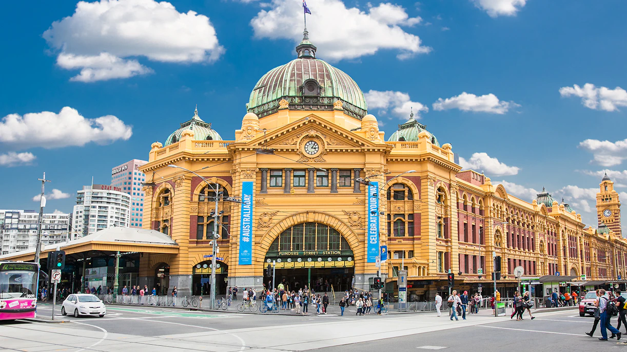 Flinders Street Station in Melbourne with people and traffic in front.