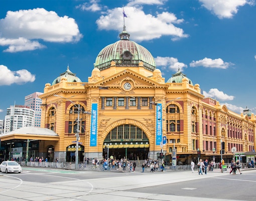 Flinders Street Station in Melbourne with people and traffic in front.