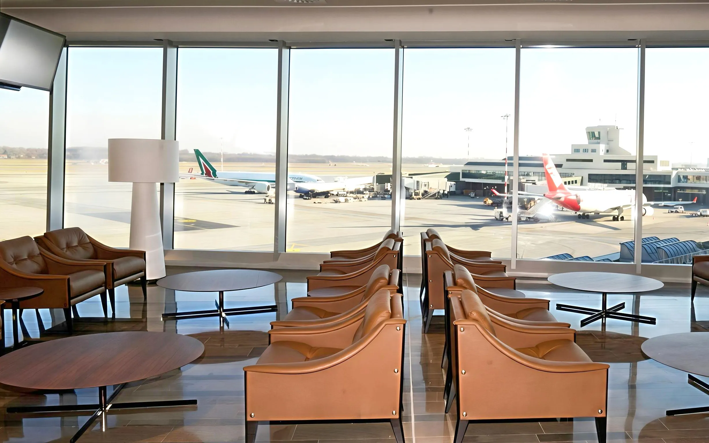 Montale Exclusive Lounge seating area with runway view at Malpensa Airport Terminal 1, Milan.