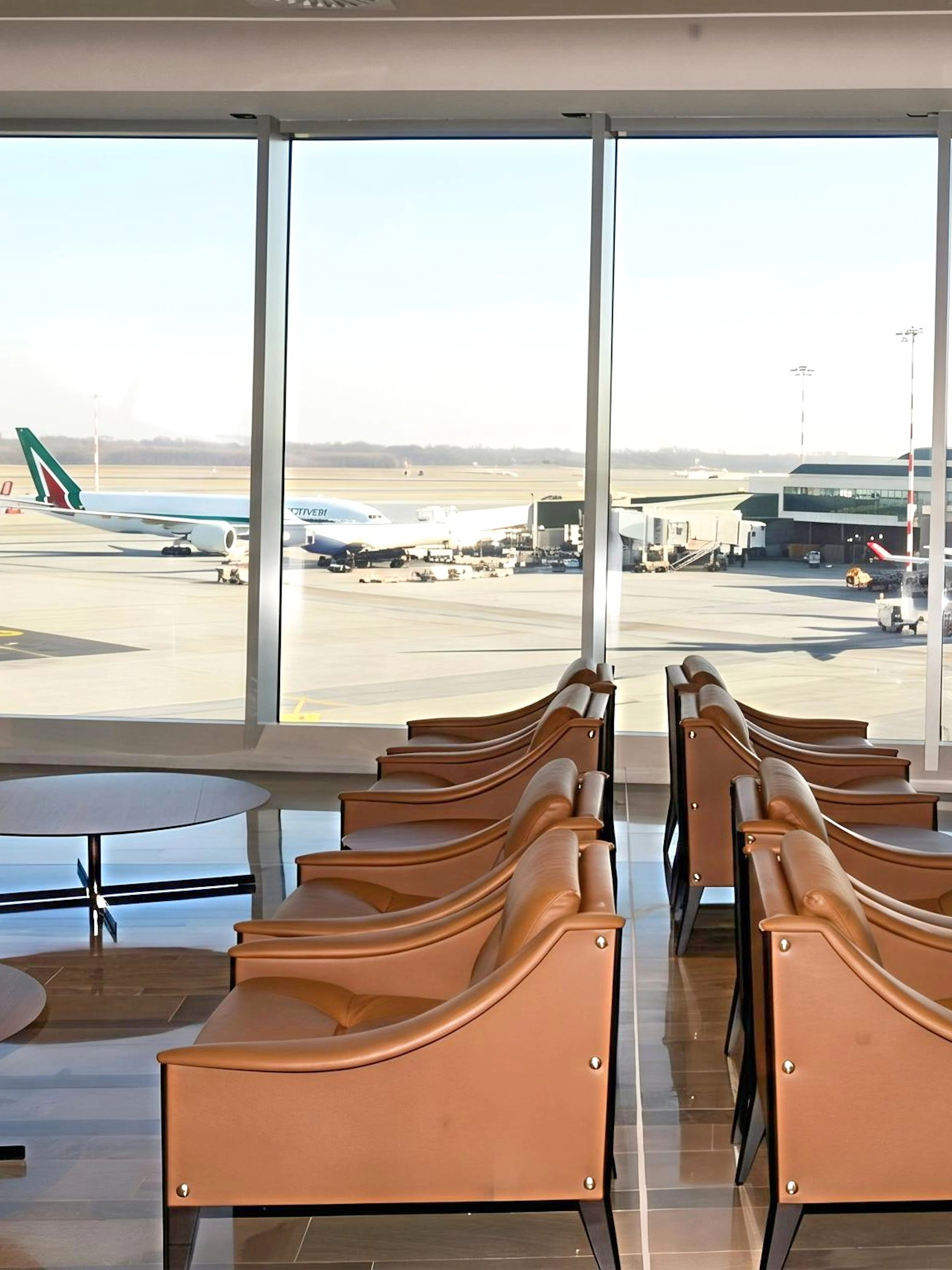 Montale Exclusive Lounge seating area with runway view at Malpensa Airport Terminal 1, Milan.