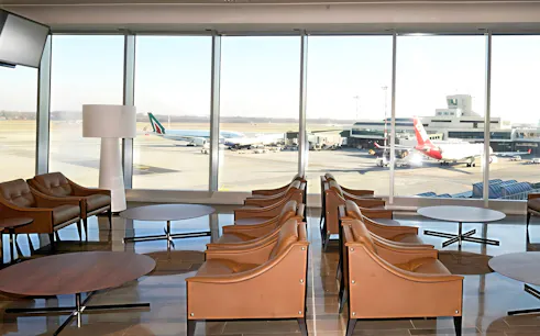 Montale Exclusive Lounge seating area with runway view at Malpensa Airport Terminal 1, Milan.