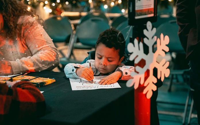 Child coloring at a holiday-themed event during the Circle Line: Harbor Lights Cruise.