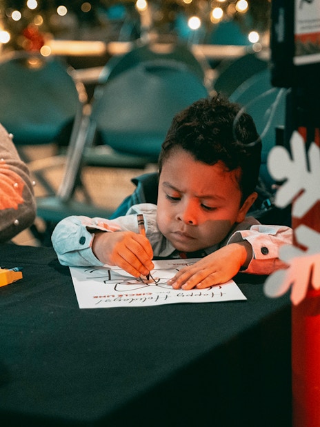 Child coloring at a holiday-themed event during the Circle Line: Harbor Lights Cruise.