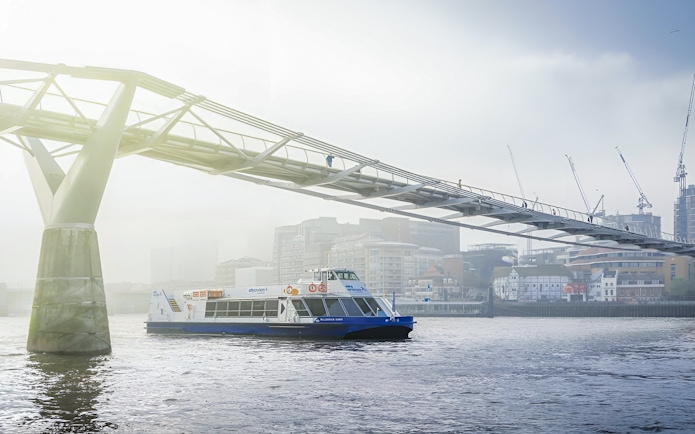 Sightseeing cruise on River Thames passing under Millennium Bridge, London.