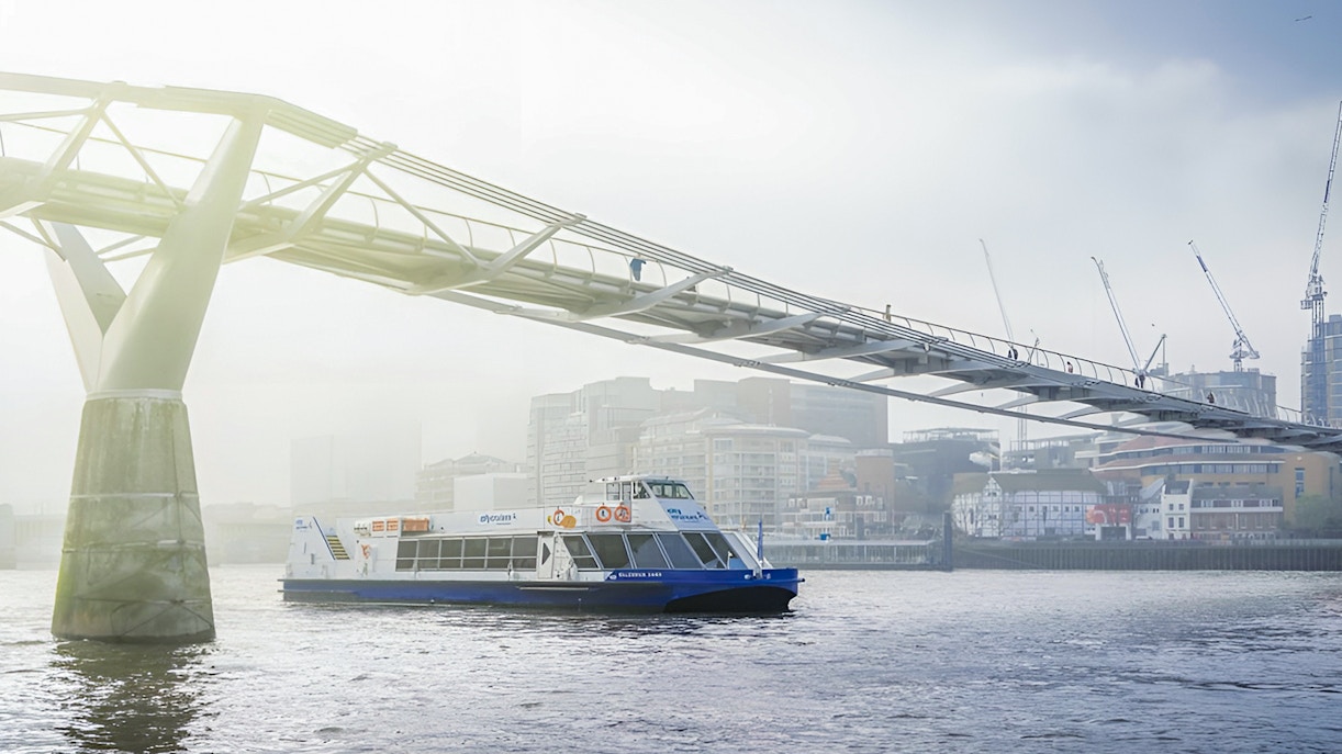 Sightseeing cruise on River Thames passing under Millennium Bridge, London.