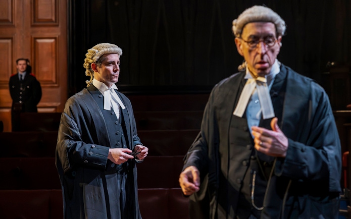 Cast of "Witness for the Prosecution" in courtroom attire on West End stage.