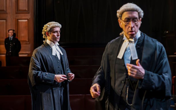 Cast of "Witness for the Prosecution" in courtroom attire on West End stage.