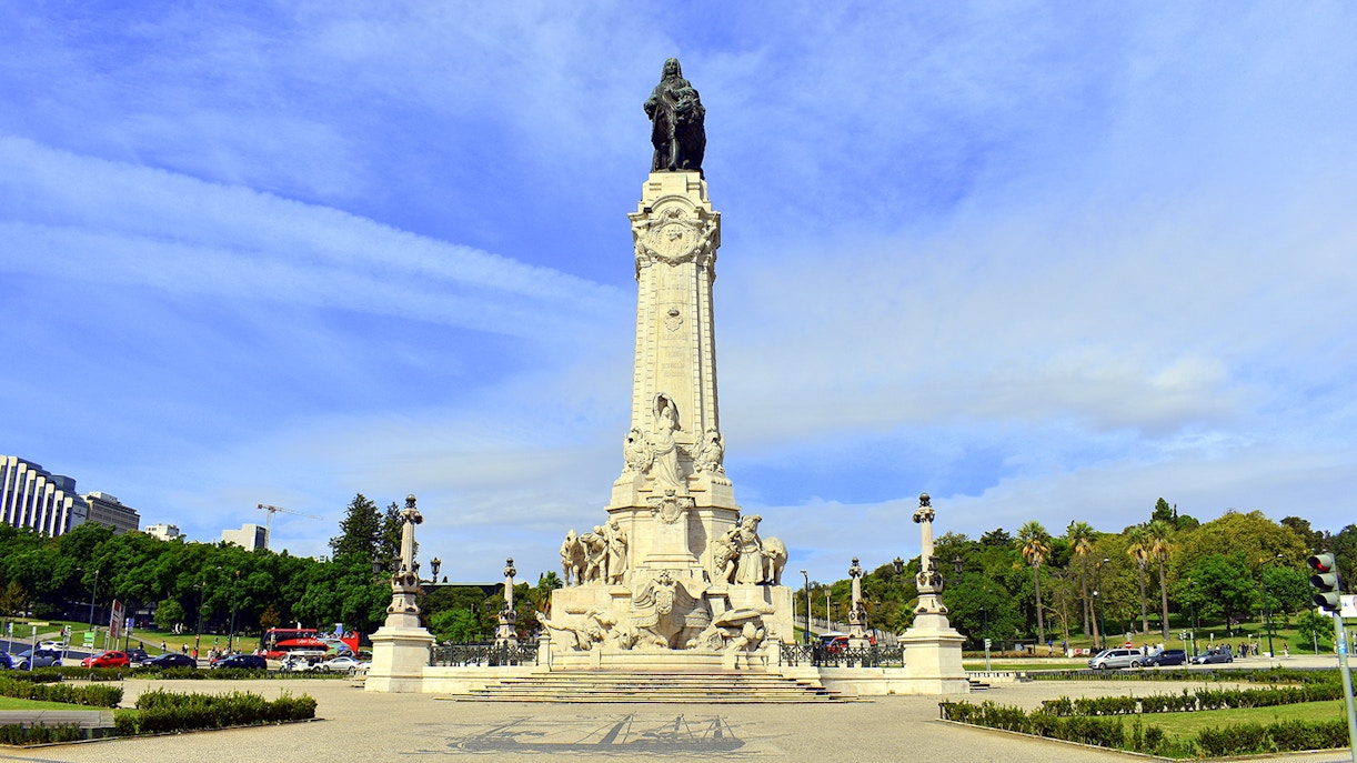 Marquês de Pombal statue in Lisbon, Portugal, surrounded by traffic and greenery.