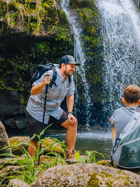 Guests hiking near Kohala Waterfalls in lush greenery.