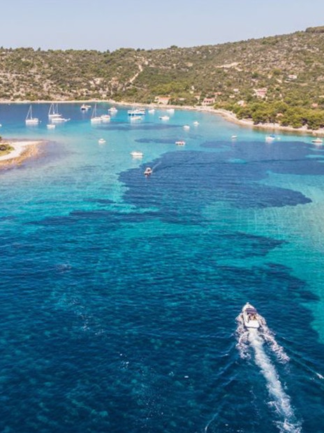 Boat navigating clear waters near Duga Bay with surrounding islands, Croatia.