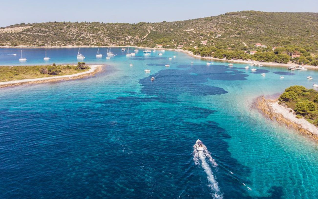 Boat navigating clear waters near Duga Bay with surrounding islands, Croatia.