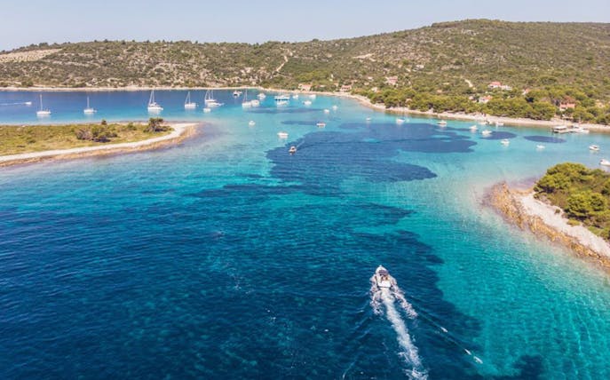 Boat navigating clear waters near Duga Bay with surrounding islands, Croatia.
