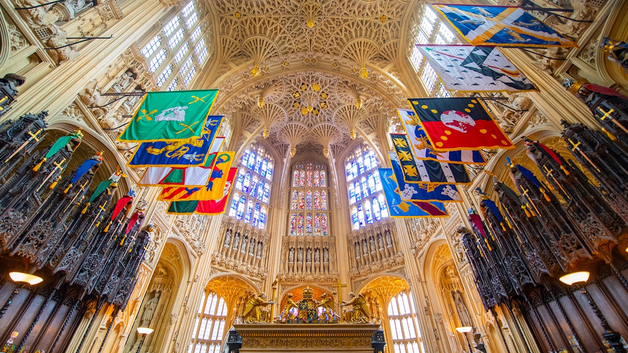 Henry VII Lady Chapel interior with ornate ceiling and colorful heraldic banners.
