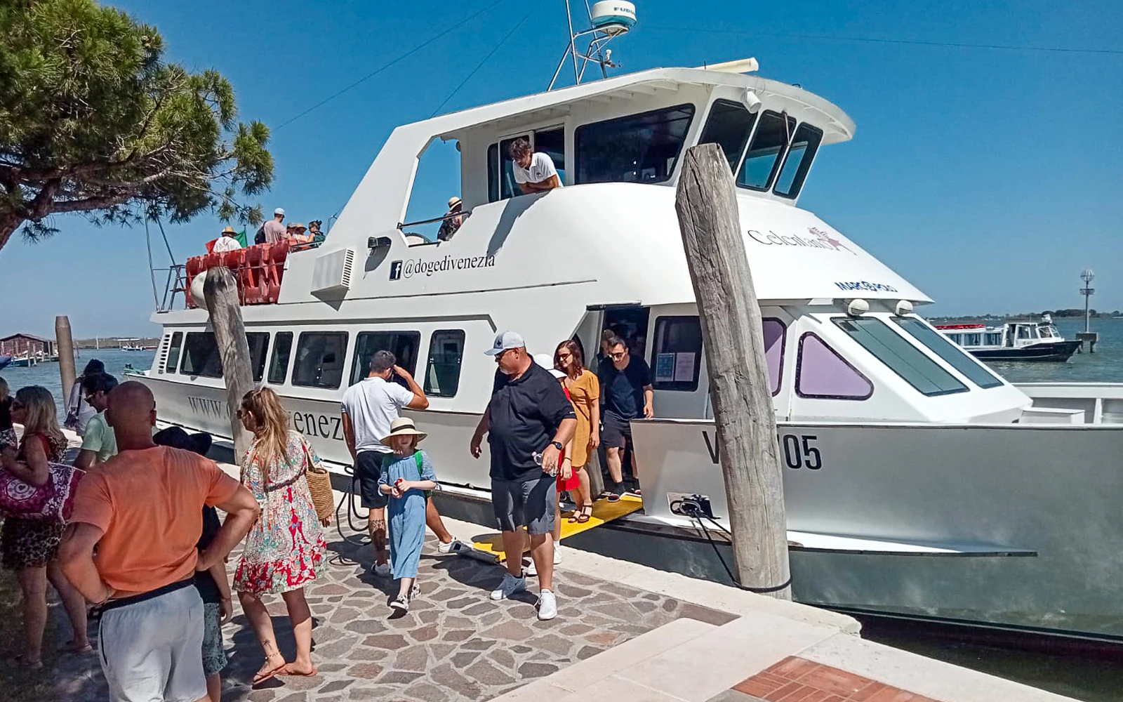 Tourists disembarking from a boat at Punta Sabbioni for a guided tour of Murano and Burano.