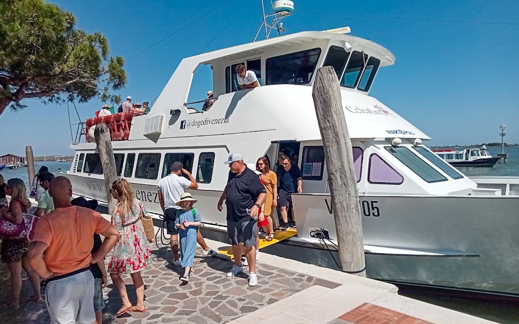 Tourists disembarking from a boat at Punta Sabbioni for a guided tour of Murano and Burano.