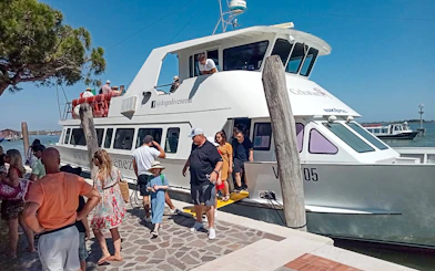 Tourists disembarking from a boat at Punta Sabbioni for a guided tour of Murano and Burano.