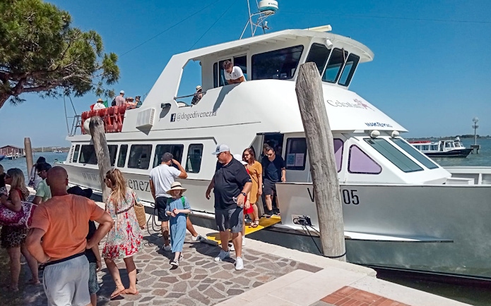 Tourists disembarking from a boat at Punta Sabbioni for a guided tour of Murano and Burano.