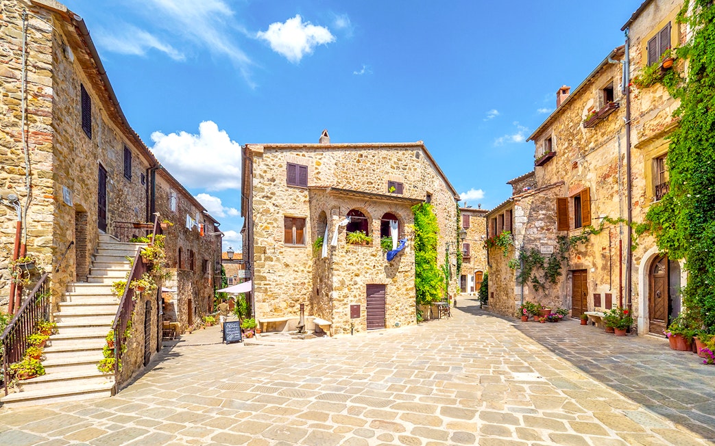 Stone buildings in a sunny Tuscan village square, part of the Highlights of Tuscany tour.