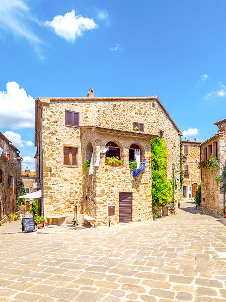 Stone buildings in a sunny Tuscan village square, part of the Highlights of Tuscany tour.