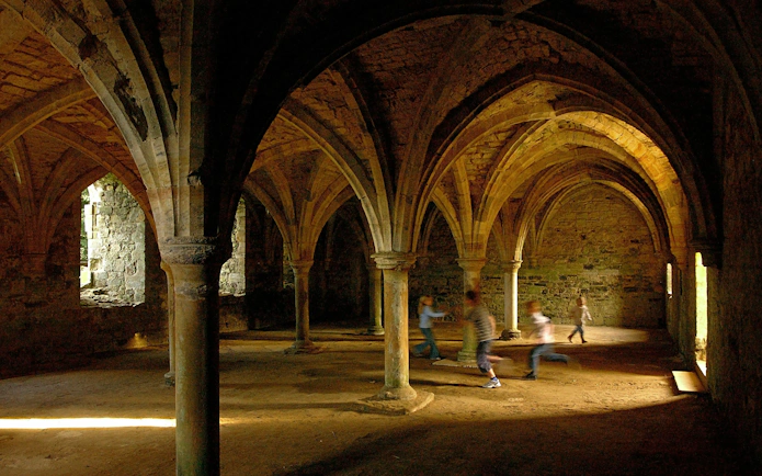 Children playing in the vaulted undercroft of Battle Abbey, England.