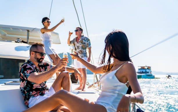 Group enjoying wine on a boat during a tour in Taormina.