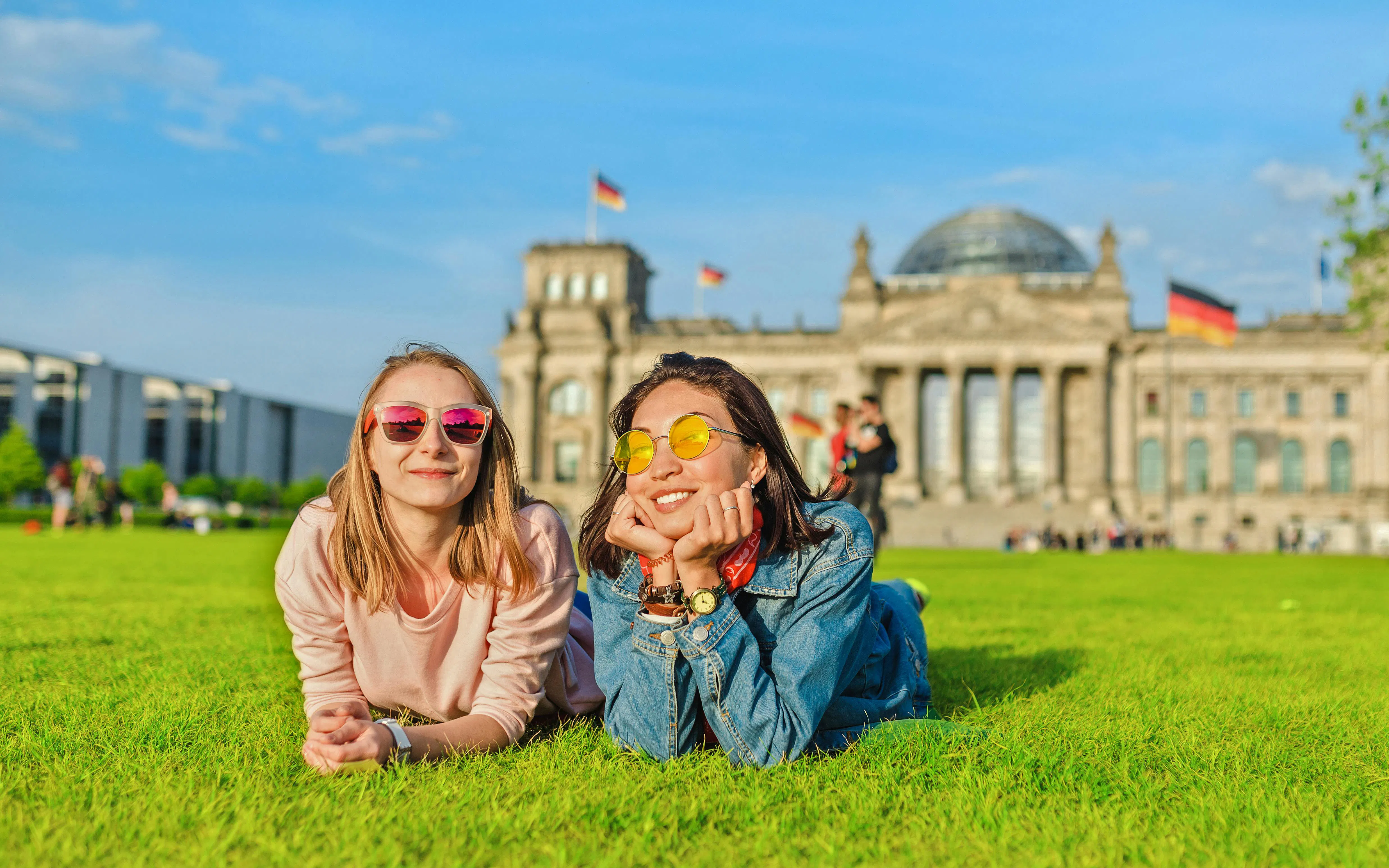 Two people lying on grass in front of the Bundestag, Berlin.