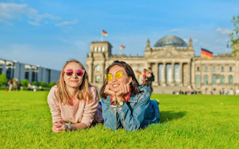 Two people lying on grass in front of the Bundestag, Berlin.