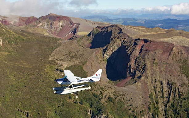 Floatplane flying over Mount Tarawera's rugged volcanic landscape during White Island tour.