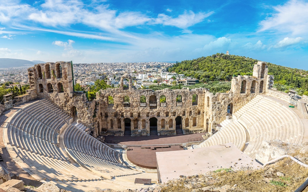 Ancient Odeon of Herodes Atticus amphitheater in Athens, Greece, with cityscape in the background.