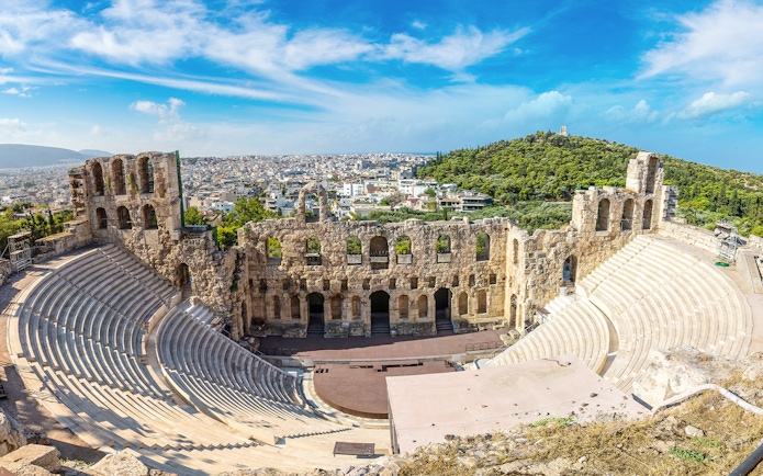 Ancient Odeon of Herodes Atticus amphitheater in Athens, Greece, with cityscape in the background.