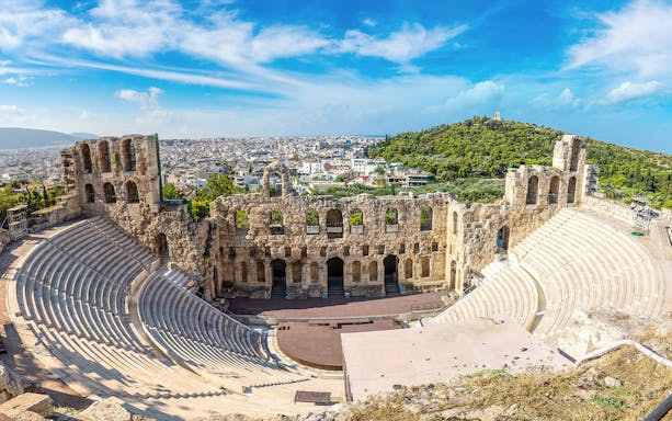 Ancient Odeon of Herodes Atticus amphitheater in Athens, Greece, with cityscape in the background.