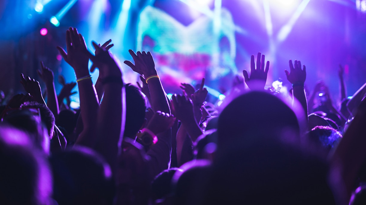 Crowd enjoying a concert with vibrant stage lights.
