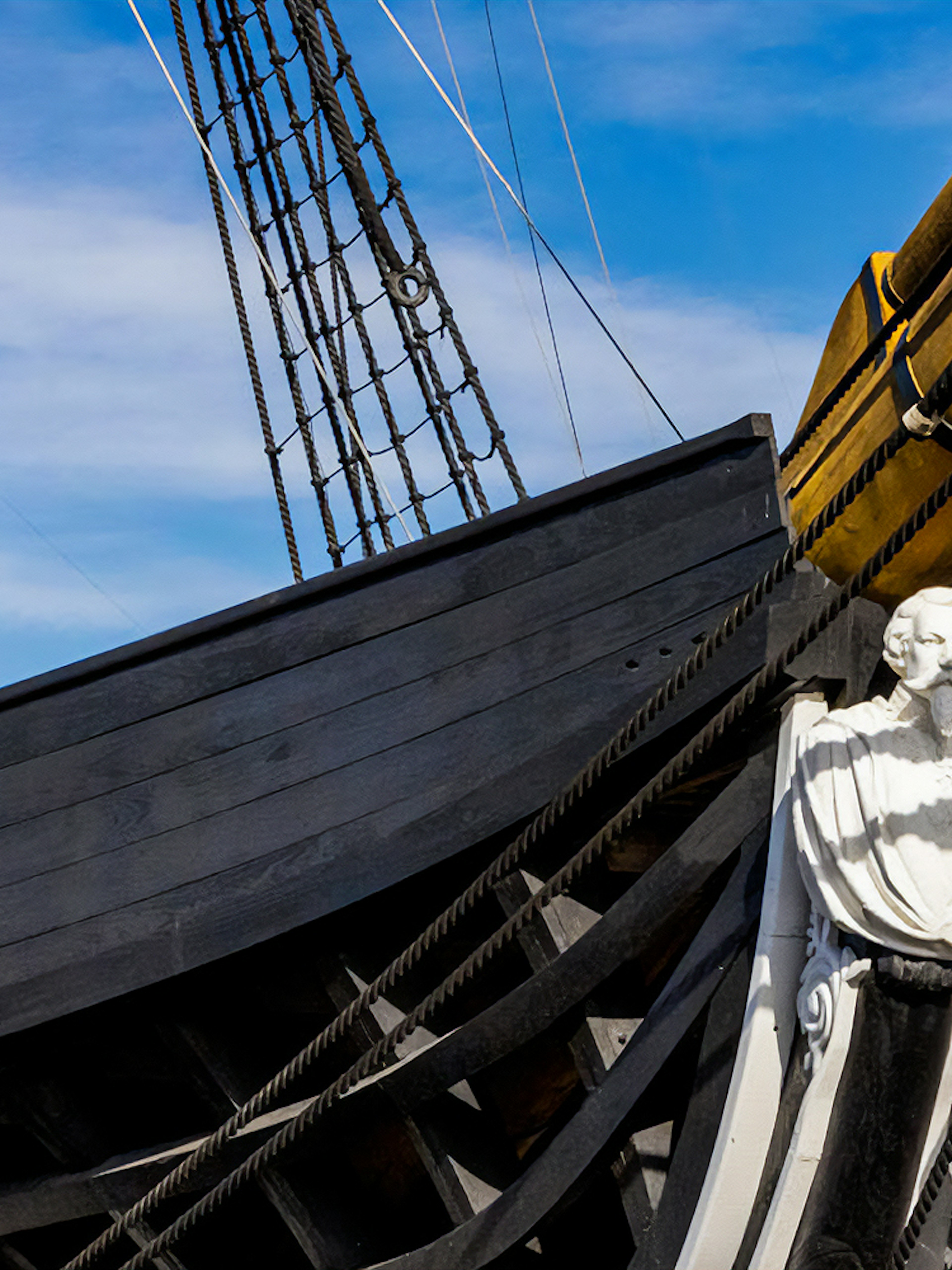 Frigate D. Fernando II e Glória bow with figurehead and rigging against blue sky.
