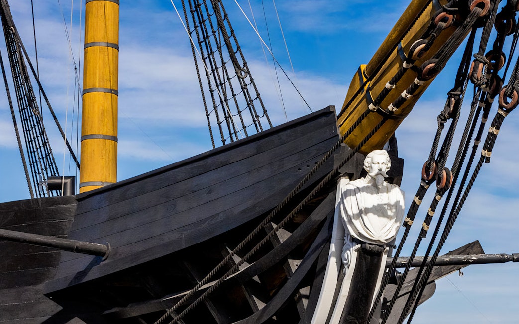 Frigate D. Fernando II e Glória bow with figurehead and rigging against blue sky.