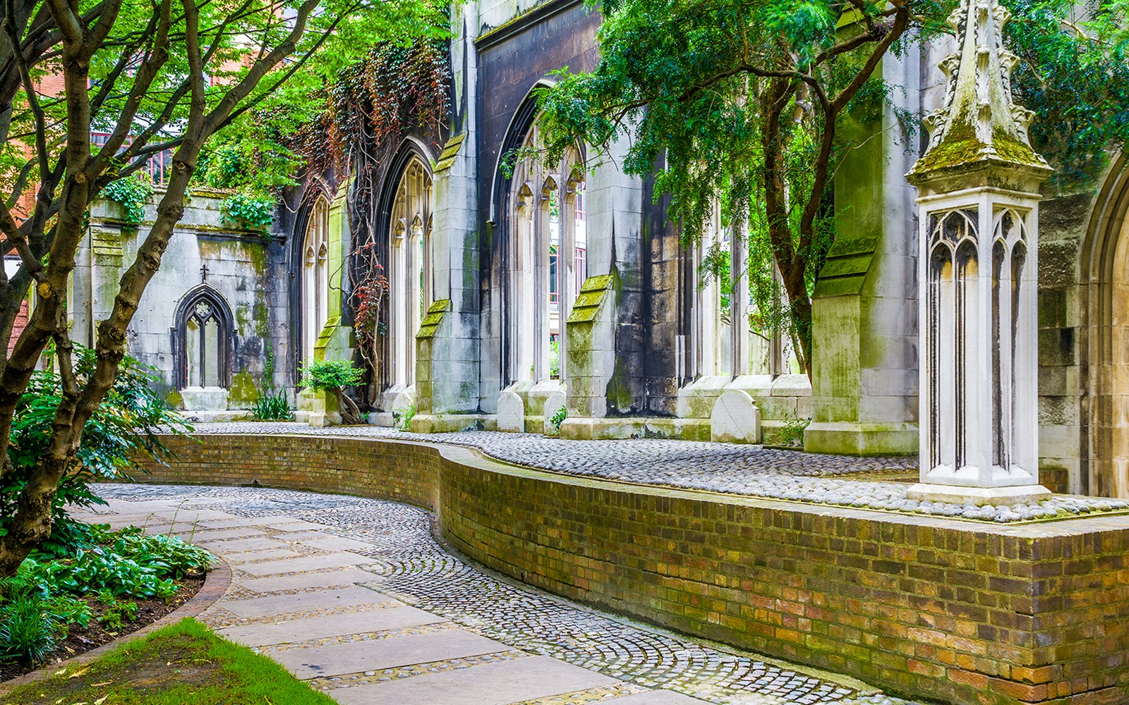 St. Dunstan-in-the-East church ruins with ivy-covered arches and cobblestone path in London.