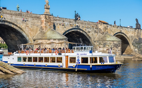 Sightseeing boat on Vltava River near Charles Bridge in Prague.
