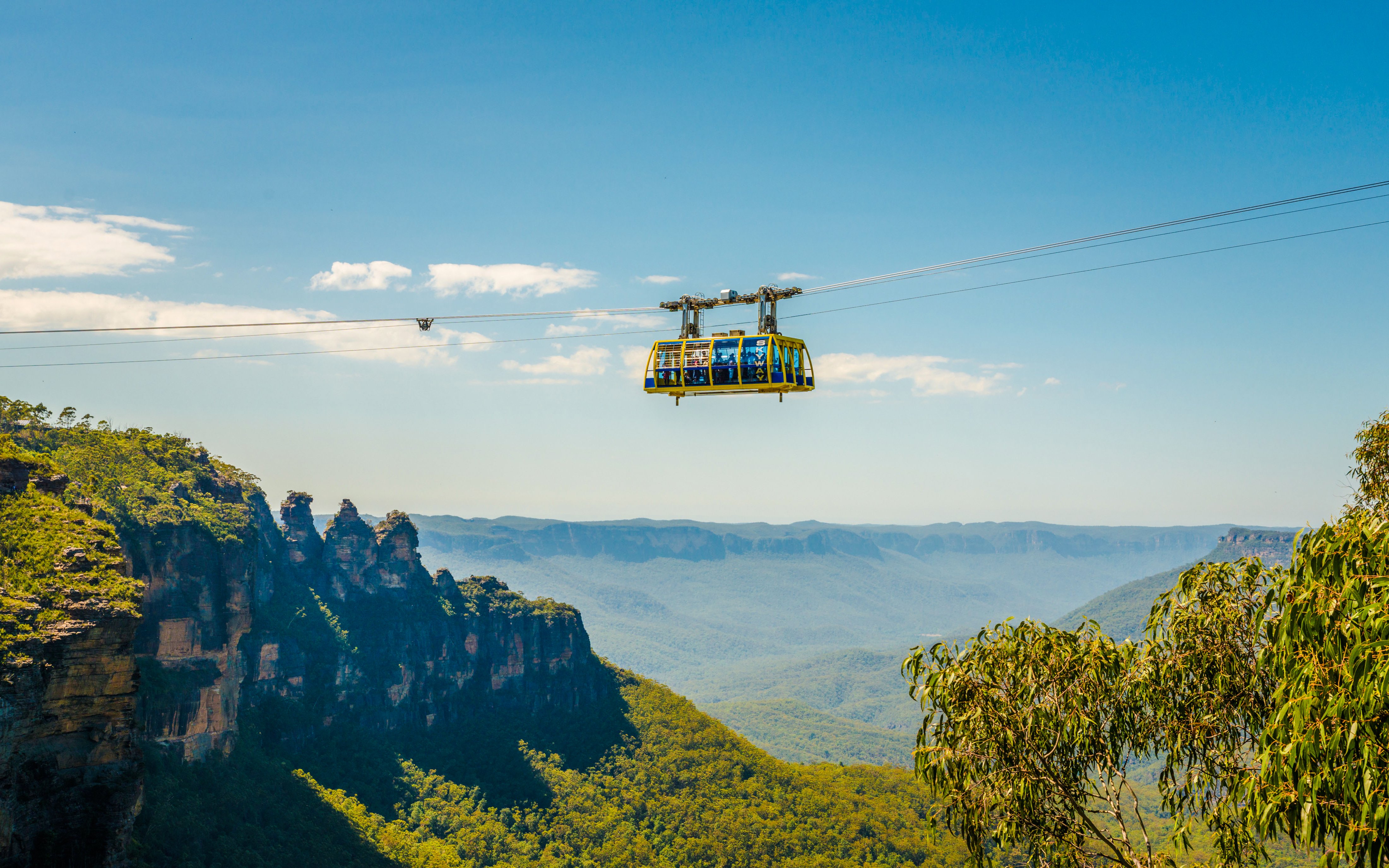 Cable car over Blue Mountains with scenic view of cliffs and forest.