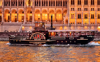 Historic cruise boat on the Danube River in Budapest with illuminated Parliament building backdrop.