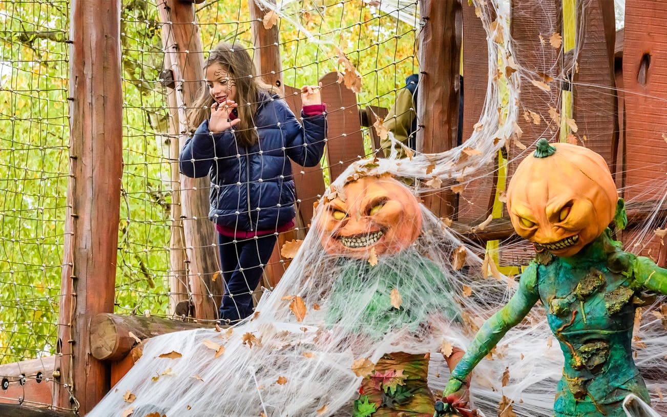 Child exploring Halloween-themed attraction with pumpkin figures at Astérix Parc.
