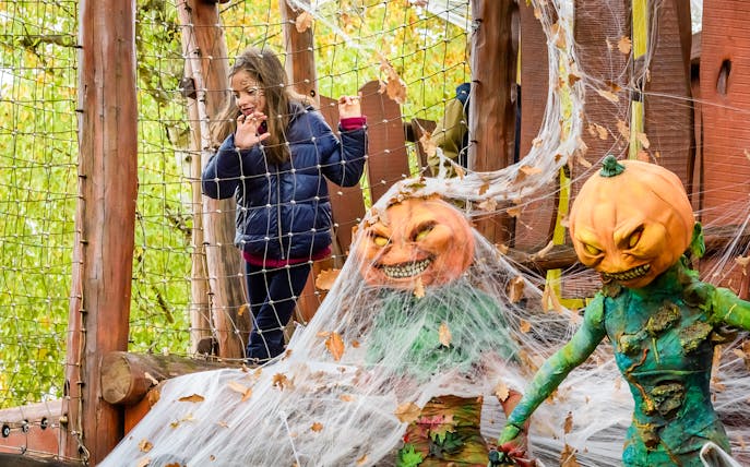 Child exploring Halloween-themed attraction with pumpkin figures at Astérix Parc.