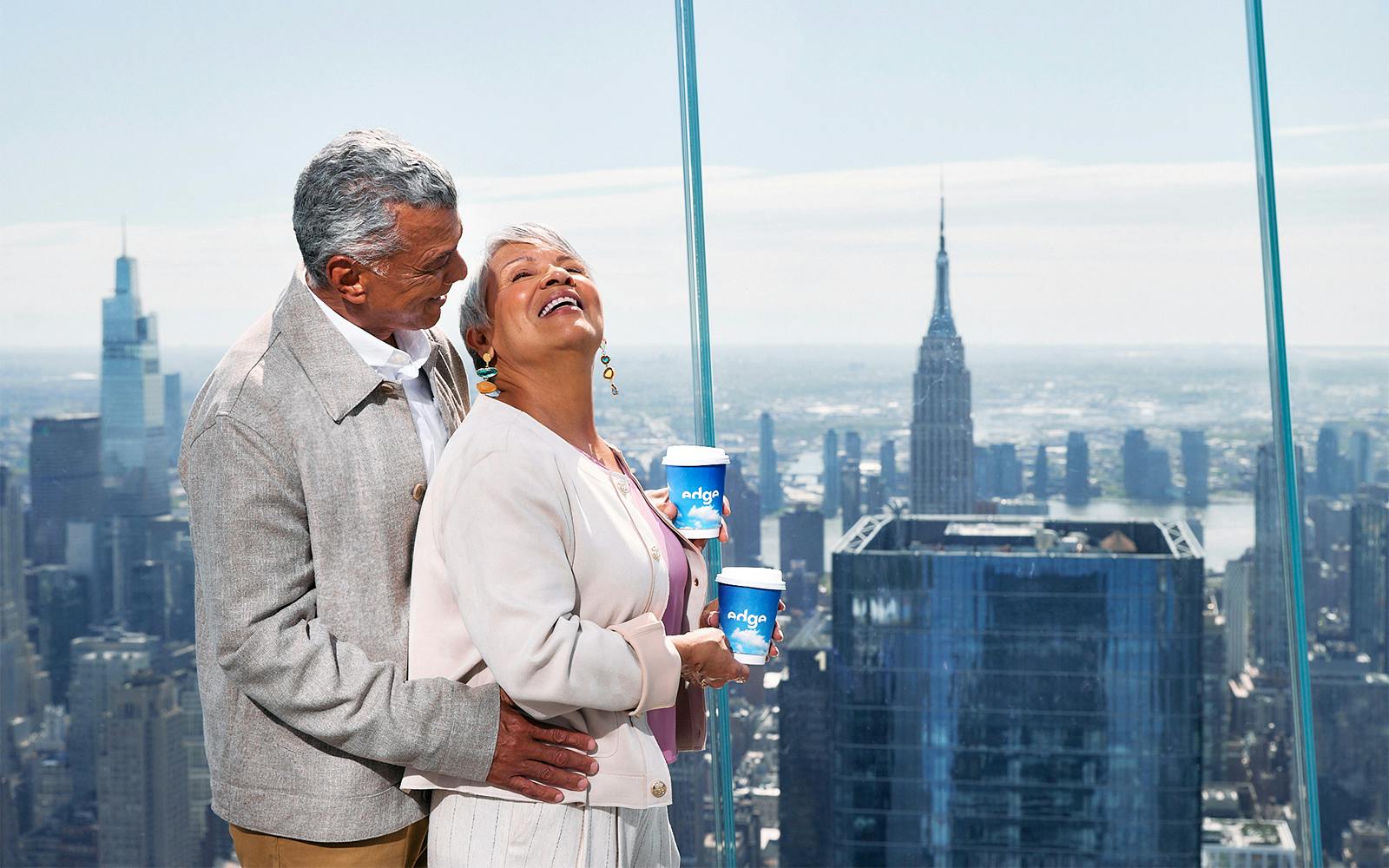 Couple enjoying view from Edge NYC with Empire State Building in background.