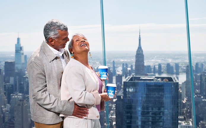 Couple enjoying view from Edge NYC with Empire State Building in background.